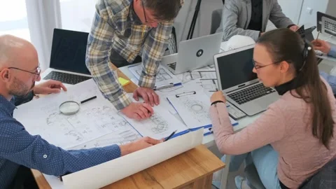 Team of architects analyzing blueprints at office desk Stock Footage 316275811