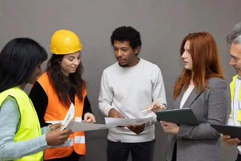 Team of architects and workers discussing blueprints on construction site Stock-Fotos
