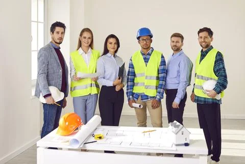 Team of architects, engineers and builders standing by office table with Fotos de archivo