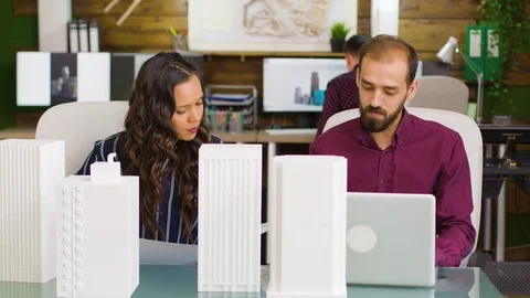 Team of architects taking notes on laptop with building models Stock Footage 117226281
