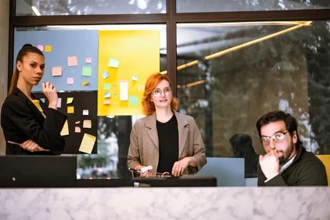 Team brainstorming session in a modern office with sticky notes on the wall and Stock Photos