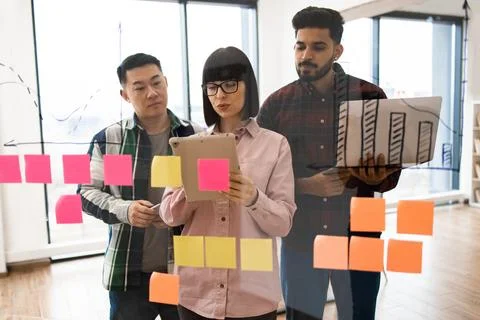 Team brainstorming with sticky notes and digital devices in modern office Stock Photos