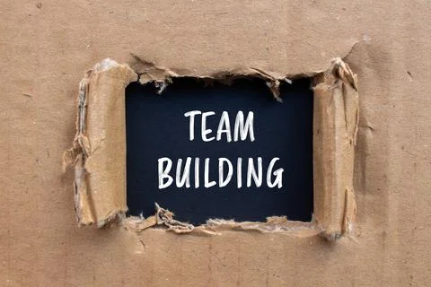 Team building message written on ripped cardboard paper with black background Fotos de archivo
