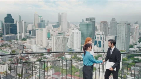 Team of business shake hands using laptop to work at rooftop city view Stock Footage 214827783