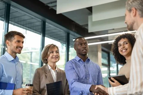 Team of businessmen shaking hands while standing in an office, finishing up.. Stock Photos