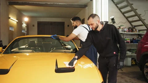 Team of car wash workers men, wearing protective clothes uniform cleaning modern Stock Footage 233821822