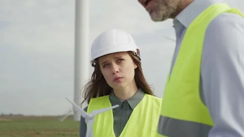 Team of caucasian engineers standing on wind turbine field and discussing Stock-Footage 221223806