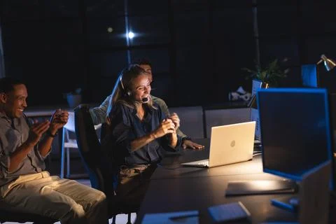 Team celebrating success at office, using laptops and headsets during night work Stock Photos