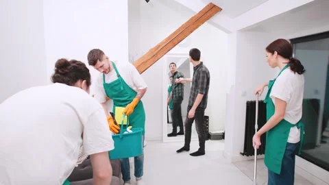 Team of cleaners discussing their tasks with a client in a bright modern home du Stock Footage 301525224