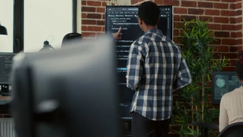 Team of coders analyzing code on wall screen tv comparing errors using digital Stock Footage 168233794