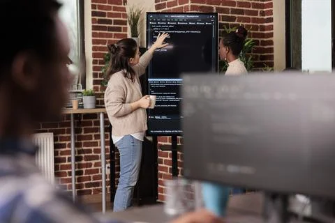 Team of coders talking about algorithms in front of big screen Stock Photos