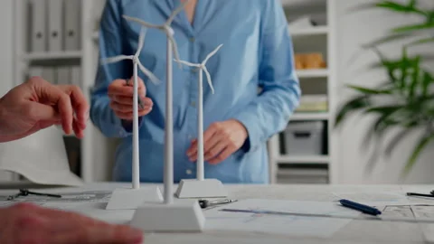 Team collaborates on renewable energy project with wind turbine models durin Stock Footage 323715458