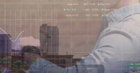 Team collaborating in office, overlaying digital interface with stock graphs and Stock Footage 308653666