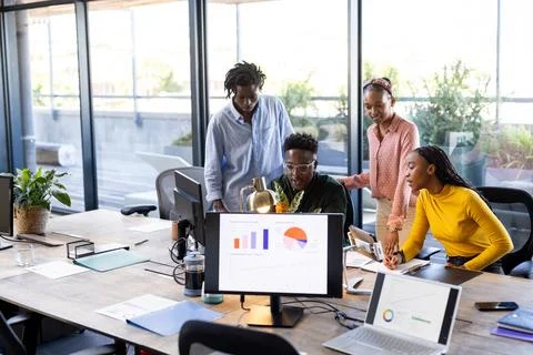 Team collaborating on project, analyzing data on computer screens in modern Fotos de archivo