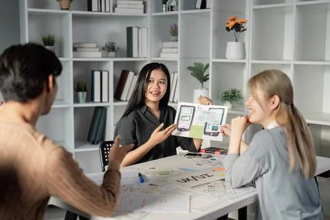 Team collaborating on UX UI presentation with prototypes and sketches. Stock Photos