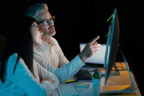 Team Collaboration on Computer in Dark Office Environment Stock Photos