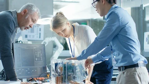 Team of Computer Engineers Lean on the Desk and Choose Printed Circuit Boards Stock Footage 85772003