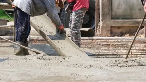 A team of construction workers is collaborating to shovel cement mix from a.. Stock Footage 300082515