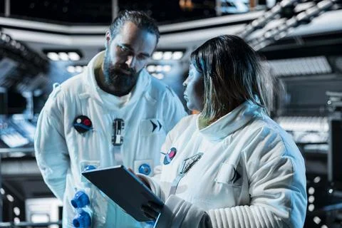 Team of cosmonauts managing systems using tablet Stock Photos