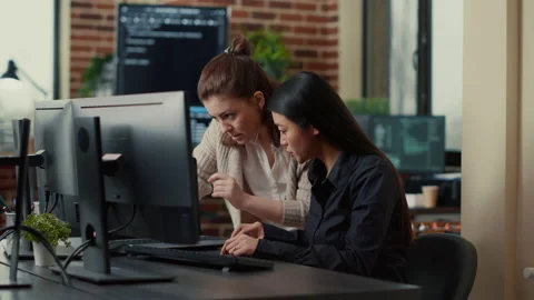 Team of coworkers comparing source codes running on laptop screen and computer Stock Footage 168248307
