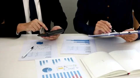 Team of coworkers studies statistical documents sitting at table in office. M Stock Footage 256743371