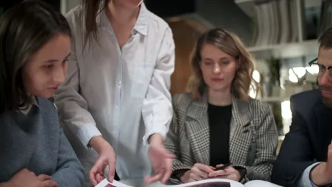 Team Of Creative Designers Are Looking At The Project Magazine, Talking About Видео 130948146