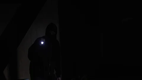 Team of dangerous masked robbers using flashlight walking in dark courtyard Stock Footage 115671032