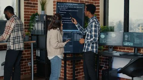 Team of database admins analyzing source code on wall screen tv comparing errors Stockfoto's