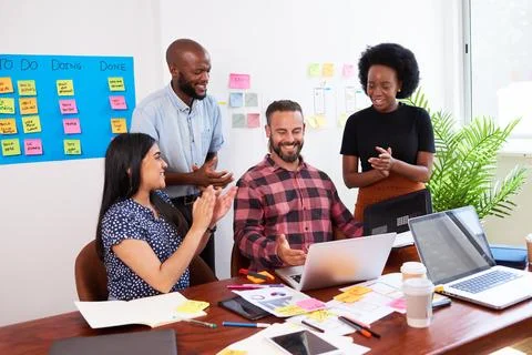 Team of developers clapping hands during brainstorm meeting in boardroom 库存照片