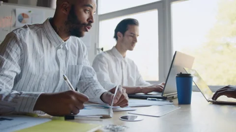 A team of diverse professionals works together in an office space, focusing on 스톡 동영상 335732207