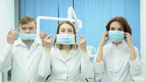 Team of doctors with arms crossed standing in masks. Media. Three doctors stand Stock Footage