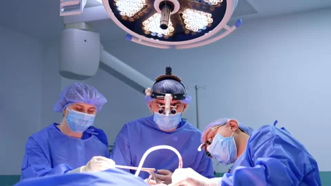 Team of doctors in blue robes working in modern surgery room. Neurosurgeon uses Stock Footage 333337026