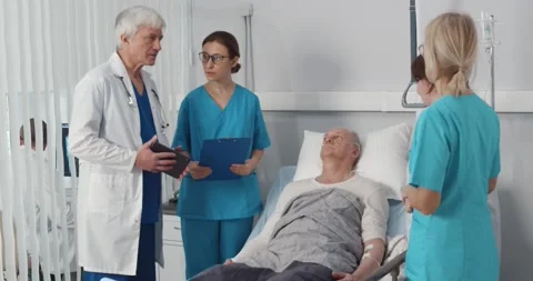 Team of doctors examining elderly patient discussing medical condition in Stock Footage 148226972