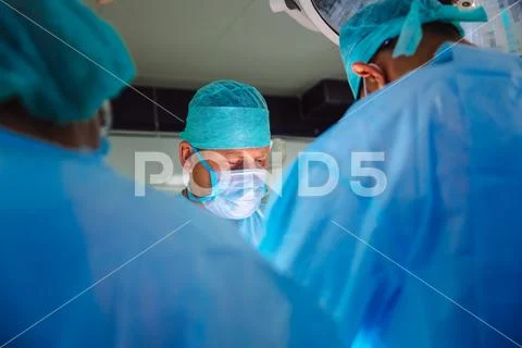 A team of doctors in sterile medical clothes perform an operation in a hospital Stock Photos