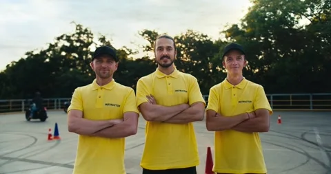 A team of driving instructors in a yellow T-shirt put their hands on their Video stock 249234931