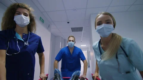 A team of emergency doctors are running down the corridor with a patient Видео 224057396