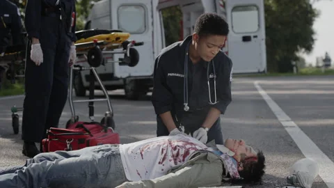 Team of EMS Paramedics trying to help car accident victim Stock Footage 164275990