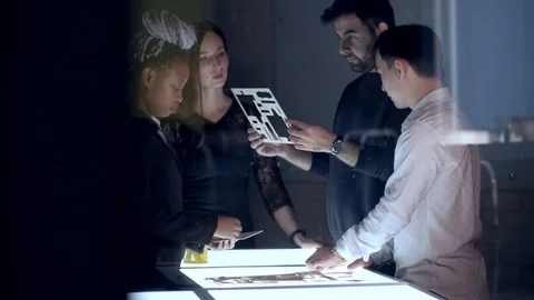 A team of engineers of architects of different races works at night realizing Stock Footage 124942778