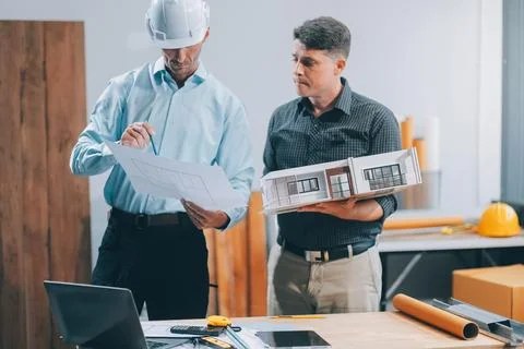 Team Engineers with draft plan of building on constructing site. Engineer w.. Fotos de archivo