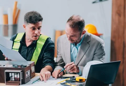 Team Engineers with draft plan of building on constructing site. Engineer w.. Fotos de archivo