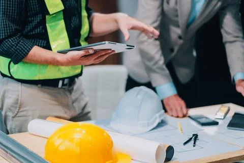 Team Engineers with draft plan of building on constructing site. Engineer w.. Fotos de archivo