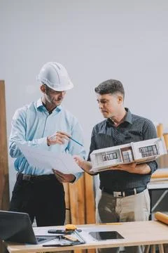 Team Engineers with draft plan of building on constructing site. Engineer w.. Fotos de archivo