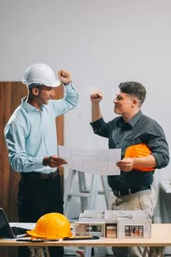 Team Engineers with draft plan of building on constructing site. Engineer w.. Fotos de archivo