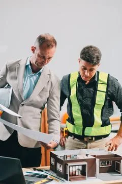 Team Engineers with draft plan of building on constructing site. Engineer w.. Fotos de archivo