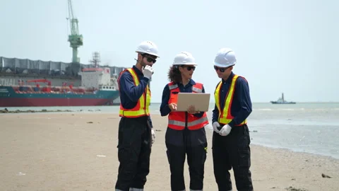 A team of engineers in safety gear walk beside the water at a port inspected 库存影片 340075615