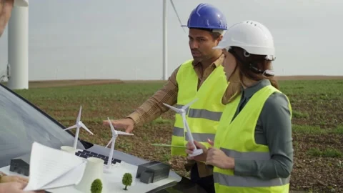 Team of engineers standing on wind turbine field and discussing Stock-Footage 221222830