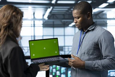 Team of engineers working in server farm, using green screen laptop 스톡 사진