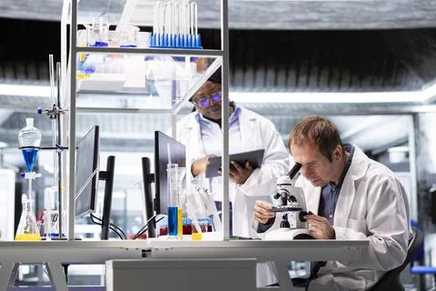 Team of experts investigate molecular samples at microscope with laboratory tray Stock Photos