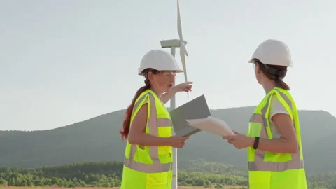 A team of female engineers are using laptops to inspect a wind turbine outdoors Stock Footage 278243454