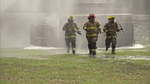 A team of firefighter walks through heavy smoke holding a rescue axe Vídeos de archivo 326217121